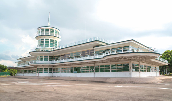 Exterior of a white Art Deco building with a tower, under a cloudy sky.